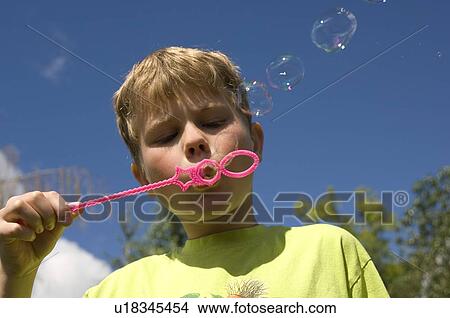 Picture -  close up young blond boy blowing bubbles male. Fotosearch