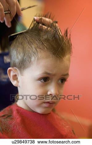 Stock Photo -  kid young boy gets hair cut haircut salon barber. Fotosearch