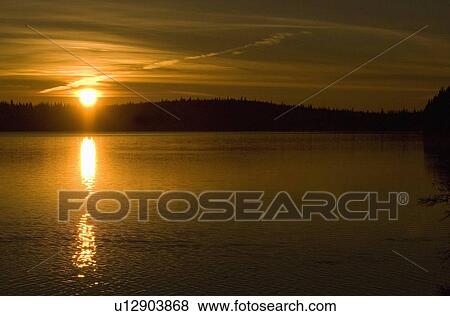 Stock Photo -  morning sunrise small alberta lake warming cool. Fotosearch
