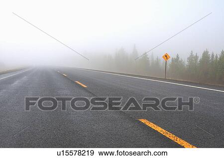 Stock Photo -  nature misty fog two lane highway in rural. Fotosearch
