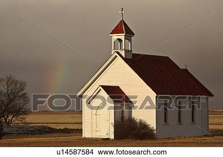 Picture -  rainbow behind saint columba church clouds field. Fotosearch