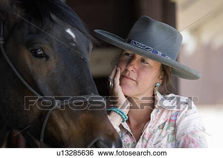 Stock Photograph -  woman horse cowgirl relaxes ranch in colorado. Fotosearch