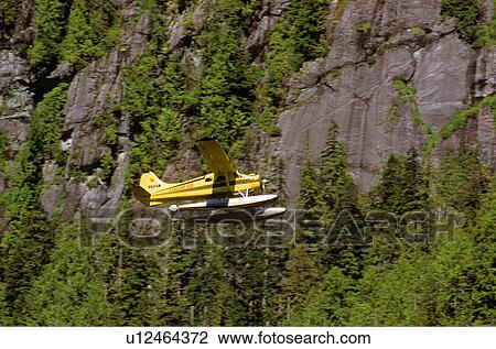 Stock Image -  yellow colored float plane gaining altitude lake. Fotosearch