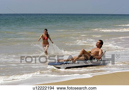 Picture - beach water couple man in mulloor kovalam waves. Fotosearch