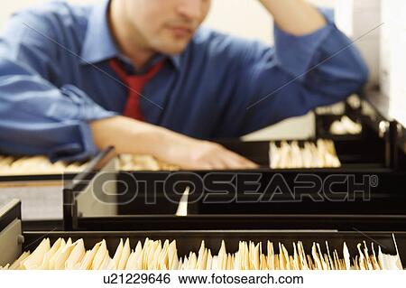 Stock Photograph -  business searching files in filling cabinet 30-34. Fotosearch