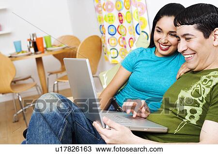 Stock Image -  computer couple laptop young looking smiling. Fotosearch