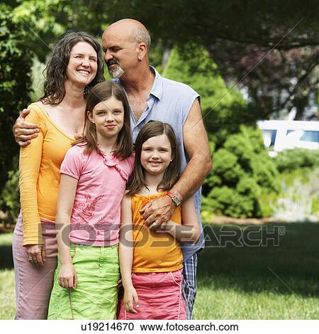 Stock Image -  couple child mature standing two daughters 10-11. Fotosearch
