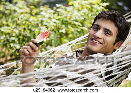 Stock Image -  food man portrait young lying in hammock holding. Fotosearch