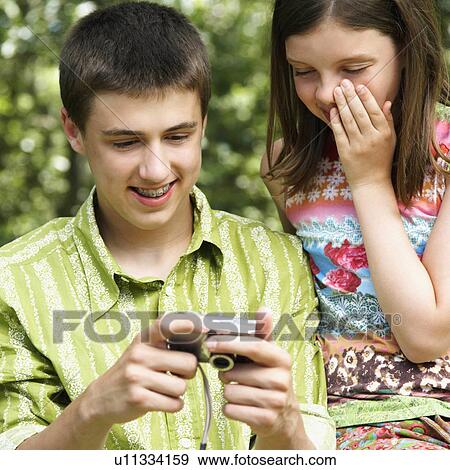 Stock Photo - girl child 10-11 teenage boy 16-17 holding digital camera. Fotosearch