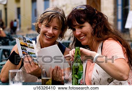 Stock Image -  girl tourist friends relax drinks look postcards. Fotosearch