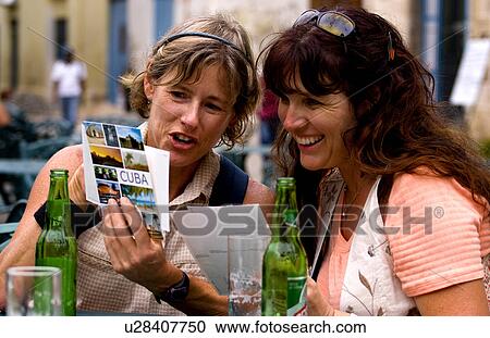 Stock Image -  girl tourist friends relax drinks look postcards. Fotosearch