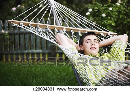 Stock Image -  portrait teenage boy lying in hammock hands head. Fotosearch