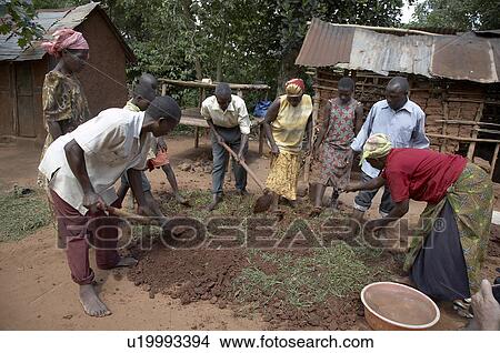 Picture -  uganda making mud wood burning cooking stove . Fotosearch