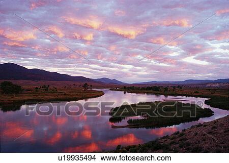 Picture -  water fall storm clouds tinted sunrise reflected. Fotosearch