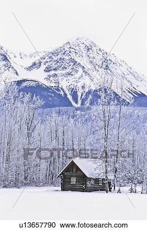 Stock Image -  winter tiny log cabin sitting under majestic day. Fotosearch