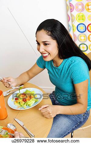 Stock Photo -  woman food young sitting table eating salad 20-24. Fotosearch