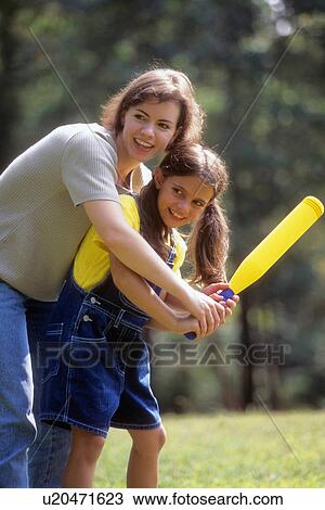 Stock Image -  woman people shows daughter use bat in baseball. Fotosearch