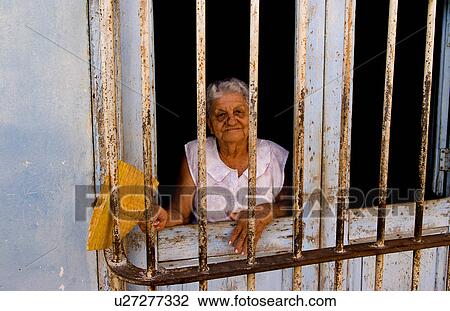 Stock Image -  woman portrait old behind bars in front trinidad. Fotosearch