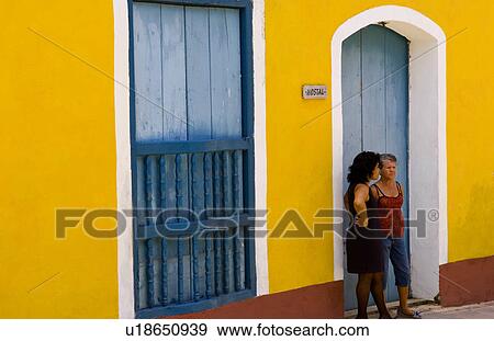 Stock Photo -  women two local talking in doorway bright yellow. Fotosearch