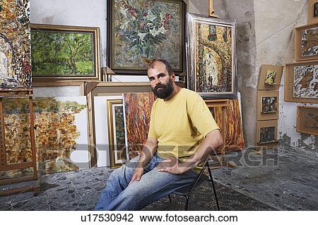 Stock Image - Artist in His Studio With Finished Paintings. Fotosearch