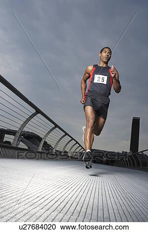 Stock Image - Athlete running on footbridge, low angle view, Millennium Bridge, London, England. Fotosearch