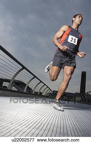 Stock Photo - Athlete running on footbridge, low angle view, Millennium Bridge, London, England. Fotosearch