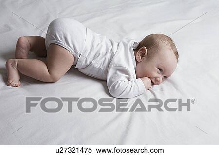 Stock Photography - Baby (1-6 months) lying on front on bed. Fotosearch