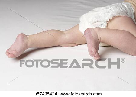 Picture - Baby (6-12 months) crawling on bed, close up of feet. Fotosearch