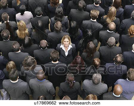 Stock Image - Back view of large group of business people, woman facing opposite direction, elevated view. Fotosearch
