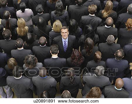 Stock Image - Back view of large group of business people, man facing opposite direction, elevated view. Fotosearch