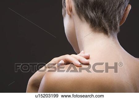 Stock Photo - Back view of young woman touching her shoulder. Fotosearch