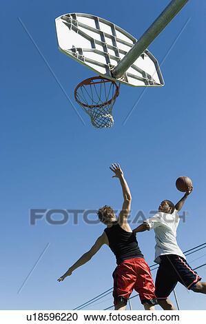 Basketball player guarding another as he tries to shoot basketball, low angle view View Large Photo Image Stock Image - Basketball player guarding another as he tries to shoot basketball, low angle view. Fotosearch