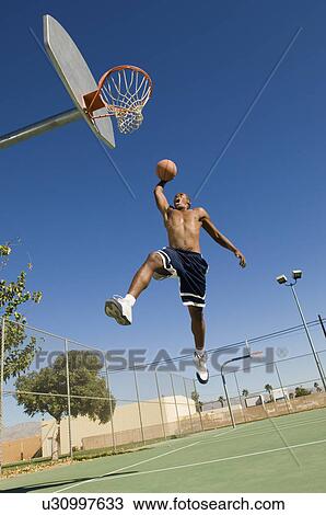 Basketball player, mid-air, dunking ball View Large Photo Image Stock Image - Basketball player, mid-air, dunking ball. Fotosearch