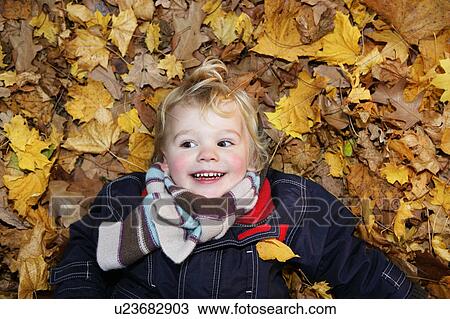 Boy (3-4) lying on ground in autumn leaves View Large Photo Image Stock Image - Boy (3-4) lying on ground in autumn leaves. Fotosearch
