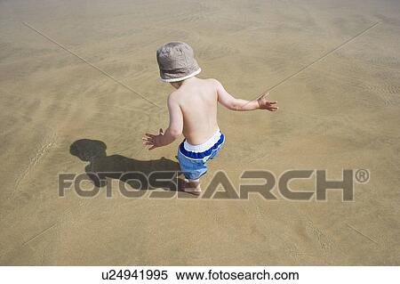 Stock Photography - Boy (3-4) playing on beach, back view. Fotosearch