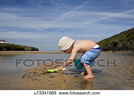 Boy (3-4) playing on beach, side view View Large Photo Image Stock Photo - Boy (3-4) playing on beach, side view. Fotosearch