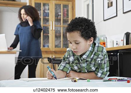 Boy (5-6) colouring with crayon, mother on phone in background View Large Photo Image Stock Photography - Boy (5-6) colouring with crayon, mother on phone in background. Fotosearch