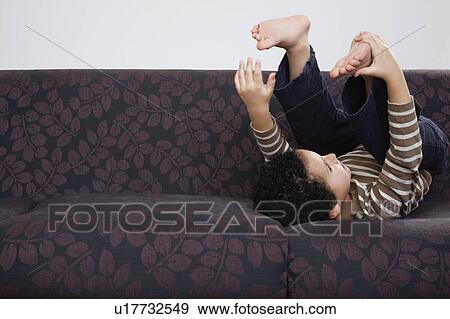 Boy (5-6) playing on sofa View Large Photo Image Stock Photo - Boy (5-6) playing on sofa. Fotosearch