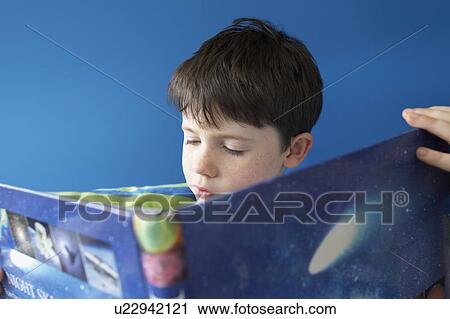 Stock Image - Boy (5-6) reading book indoors, close-up. Fotosearch