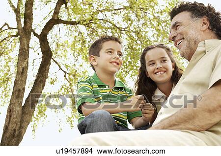 Picture - Boy (7-9) and girl (10-12) with grandfather, low angle view.. Fotosearch