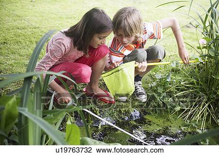Boy and girl (7-9) with fishing net by stream View Large Photo Image Stock Image - Boy and girl (7-9) with fishing net by stream. Fotosearch
