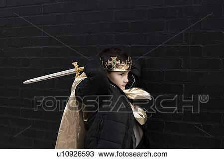 Stock Image - Boy dressed up as king with sword. Fotosearch