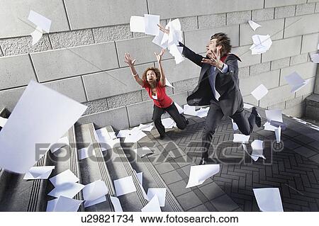 Busines man and woman catching falling paperwork on steps View Large Photo Image Picture - Busines man and woman catching falling paperwork on steps. Fotosearch