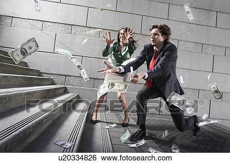 Stock Photograph - Busines man and woman catching falling money on steps. Fotosearch