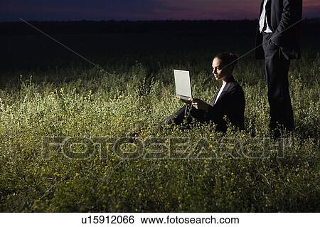 Stock Photograph - Business couple using laptop in field. Fotosearch
