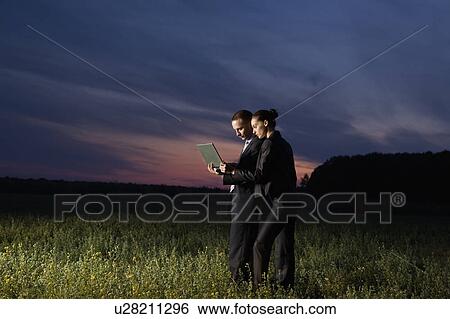 Business couple using laptop in field View Large Photo Image Stock Photograph - Business couple using laptop in field. Fotosearch