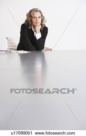 Stock Image - Business Executive Sitting in Boardroom, hand on chin. Fotosearch