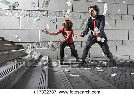 Business man and woman catching falling money on steps View Large Photo Image Stock Photo - Business man and woman catching falling money on steps. Fotosearch