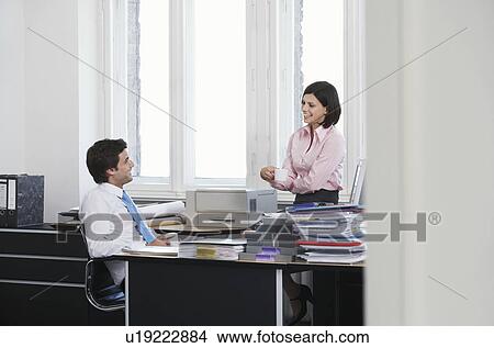 Business man and woman talking in office, smiling View Large Photo Image Picture - Business man and woman talking in office, smiling. Fotosearch