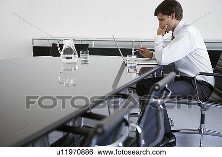 Stock Photograph - Business man using laptop at conference table. Fotosearch